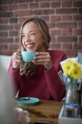 Frau sitzt im Café, trinkt Kaffee, lächelt - CUF45115