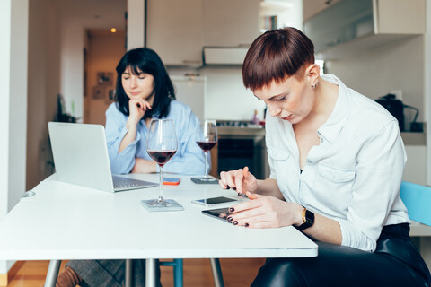Frauen am Tisch sitzend mit Laptop und digitalem Tablet, lizenzfreies Stockfoto