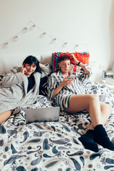 Women relaxing on bed using laptop and mobile phone - CUF45147