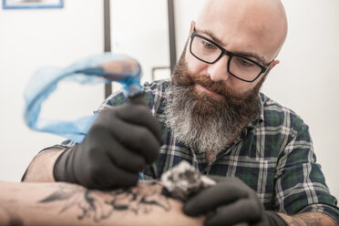 Tattooist drawing on arm of client - CUF45162