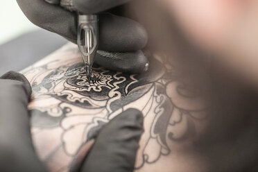 Tattooist drawing on arm of client - CUF45163