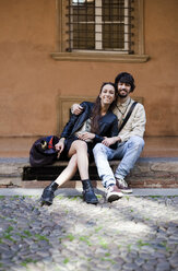 Portrait of happy young couple sitting on steps outdoors - GIOF04665