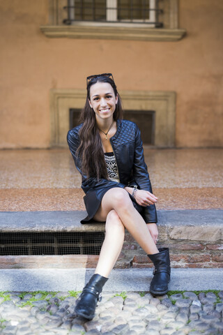 Portrait of fashionable young woman sitting on step stock photo