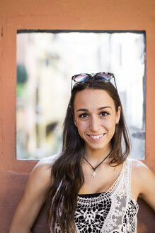 Porträt einer lächelnden jungen Frau mit braunen Haaren und Augen - GIOF04674