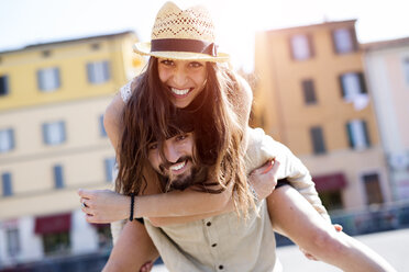 Portrait of happy young man giving his girlfriend a piggyback ride - GIOF04679