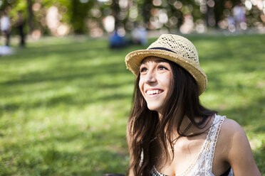 Porträt einer glücklichen jungen Frau in einem Park, die etwas beobachtet - GIOF04688