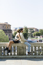 Young couple relaxing back to back on balustrade - GIOF04696