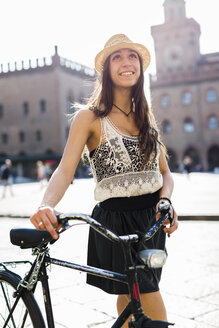 Italy, Bologna, portrait of fashionable young woman with bicycle in the city - GIOF04706