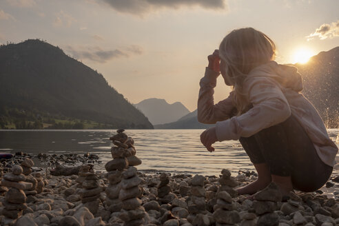 Austria, Ausseer Land, Girl building cairns at lakeshore - HAMF00382