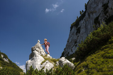 Österreich, Ausseer Land, Mädchen klettert auf Felsen in den Bergen - HAMF00387