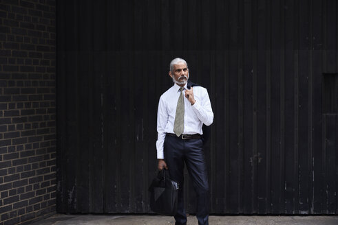 Porträt eines stilvollen älteren Geschäftsmannes mit grauem Haar vor dunklem Hintergrund - IGGF00625