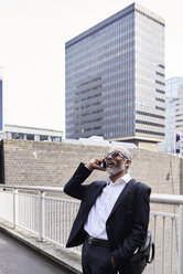 UK, London, laughing senior businessman on the phone outdoors - IGGF00631