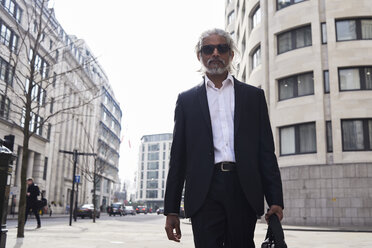 UK, London, UK, portrait of senior businessman walking in the city - IGGF00645