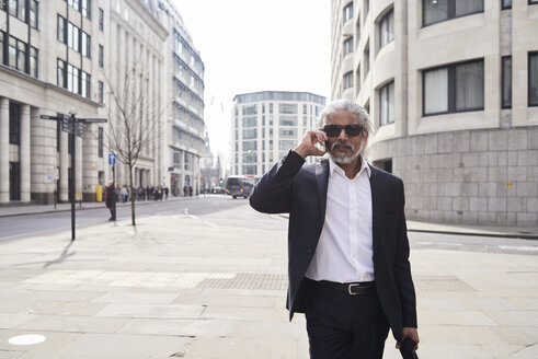 UK, London, Porträt eines älteren Geschäftsmannes mit Sonnenbrille am Telefon - IGGF00648