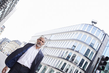 UK, London, portrait of grey-haired senior businessman walking at financial district - IGGF00659