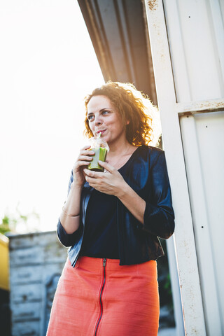 Porträt einer Frau, die einen grünen Smoothie im Freien trinkt, lizenzfreies Stockfoto