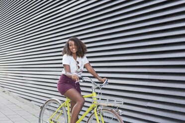 Porträt einer lächelnden jungen Frau beim Fahrradfahren - JUNF01473