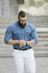 Bearded hipster businessman checking the time - FMGF00016