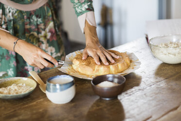 Junge Frau schneidet selbstgebackenen Kuchen an, Teilansicht - ALBF00599