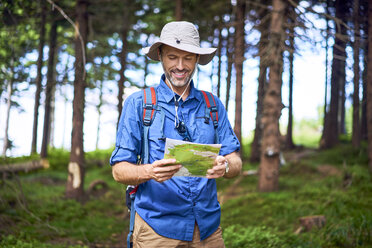 Lächelnder Mann, der bei einer Wanderung im Wald eine Karte betrachtet - BSZF00661