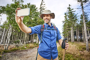 Man taking a selfie with his cell phone during hiking trip - BSZF00667