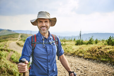 Porträt eines lächelnden Mannes beim Wandern in den Bergen - BSZF00668