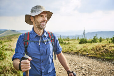 Porträt eines lächelnden Mannes beim Wandern in den Bergen - BSZF00669
