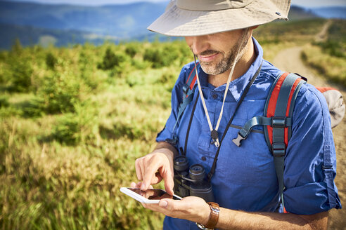 Mann überprüft sein Handy während einer Wanderung - BSZF00676