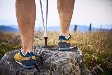 Nahaufnahme eines Mannes, der beim Wandern auf einem Baumstumpf steht - BSZF00691