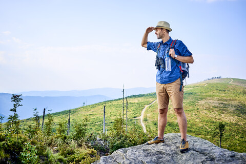 Mann bewundert die Aussicht auf die Berge beim Wandern, lizenzfreies Stockfoto