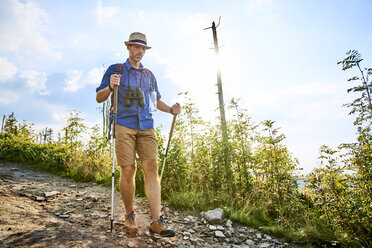 Mann geht vorsichtig mit Wanderstöcken auf einem Wanderweg - BSZF00708