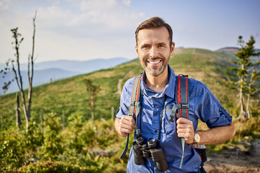 Porträt eines lächelnden Mannes beim Wandern in den Bergen - BSZF00717