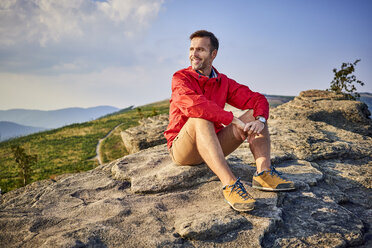 Mann sitzt auf einem Felsen und genießt die Aussicht beim Wandern - BSZF00723