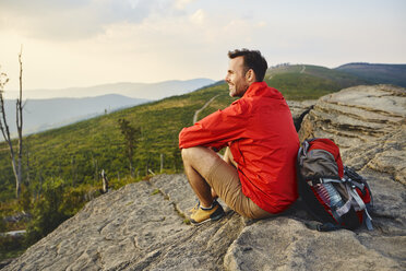 Mann sitzt auf einem Felsen und genießt die Aussicht beim Wandern - BSZF00728