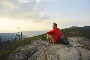 Mann sitzt auf einem Felsen und genießt die Aussicht beim Wandern - BSZF00729