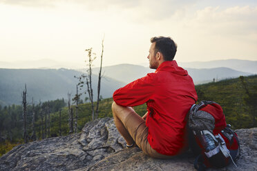 Mann sitzt auf einem Felsen und genießt die Aussicht beim Wandern - BSZF00730