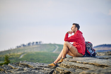 Mann sitzt auf einem Felsen und genießt die Aussicht beim Wandern - BSZF00734