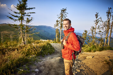 Porträt eines lächelnden Mannes beim Wandern in den Bergen - BSZF00738