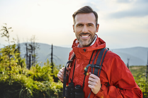 Porträt eines lächelnden Mannes beim Wandern in den Bergen, lizenzfreies Stockfoto