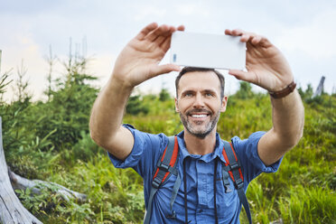 Man taking a selfie with his cell phone during hiking trip - BSZF00746