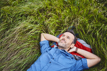 Relaxed man lying in grass enjoying hiking trip - BSZF00750