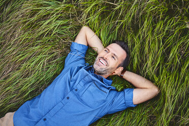 Relaxed happy man lying in grass - BSZF00751