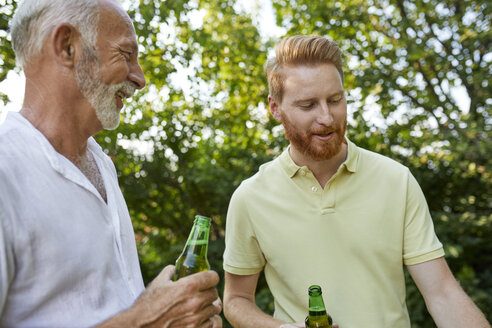 Senior father and adult son having a beer during barbecue in garden - ZEDF01580