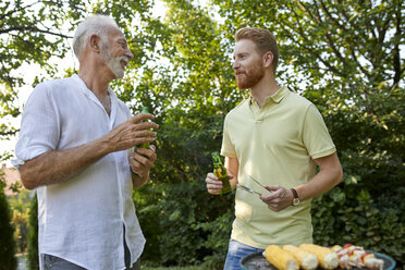 Älterer Vater und erwachsener Sohn beim Grillen und Reden im Garten - ZEDF01581