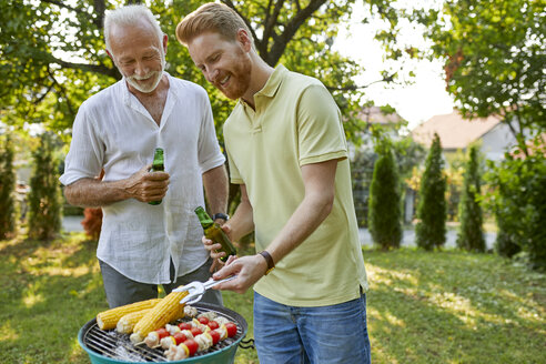 Senior father and adult son having a barbecue in garden - ZEDF01584
