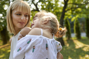 Happy mother carrying her daughter in garden - ZEDF01594