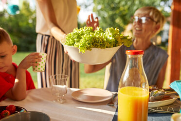 Frau serviert Salat auf einer Gartenparty - ZEDF01611