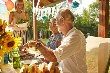 Happy woman serving salad on a garden party - ZEDF01613