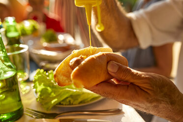 Älterer Mann bei der Zubereitung eines Hotdogs auf einer Gartenparty - ZEDF01619