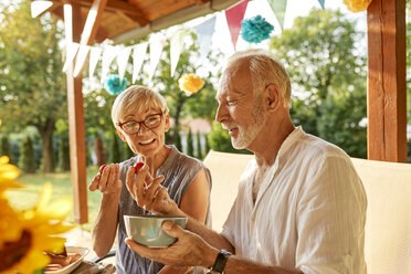 Seniorenpaar isst Tomaten auf einer Gartenparty - ZEDF01636